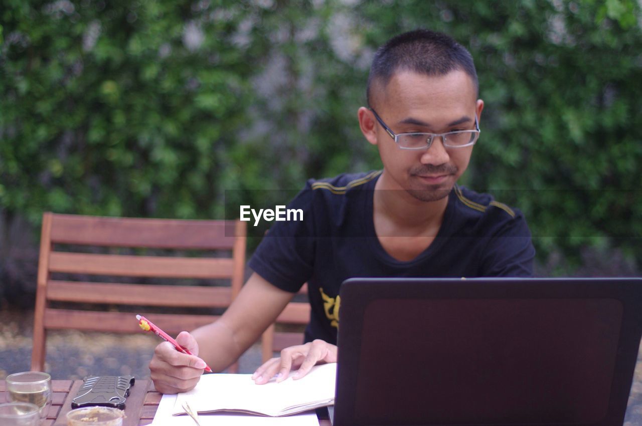 Man using laptop while sitting outdoors