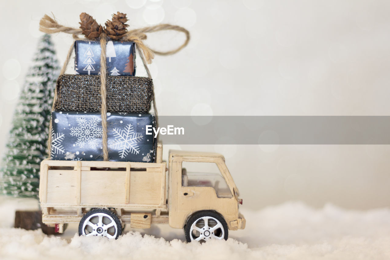 Christmas truck with christmas gifts on snowy road with christmas tree on the background