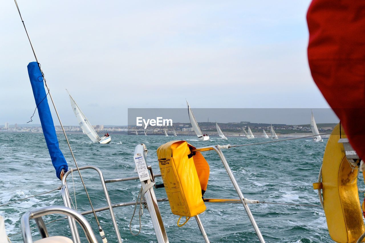 CLOSE-UP OF YELLOW SHIP SAILING ON SEA AGAINST SKY