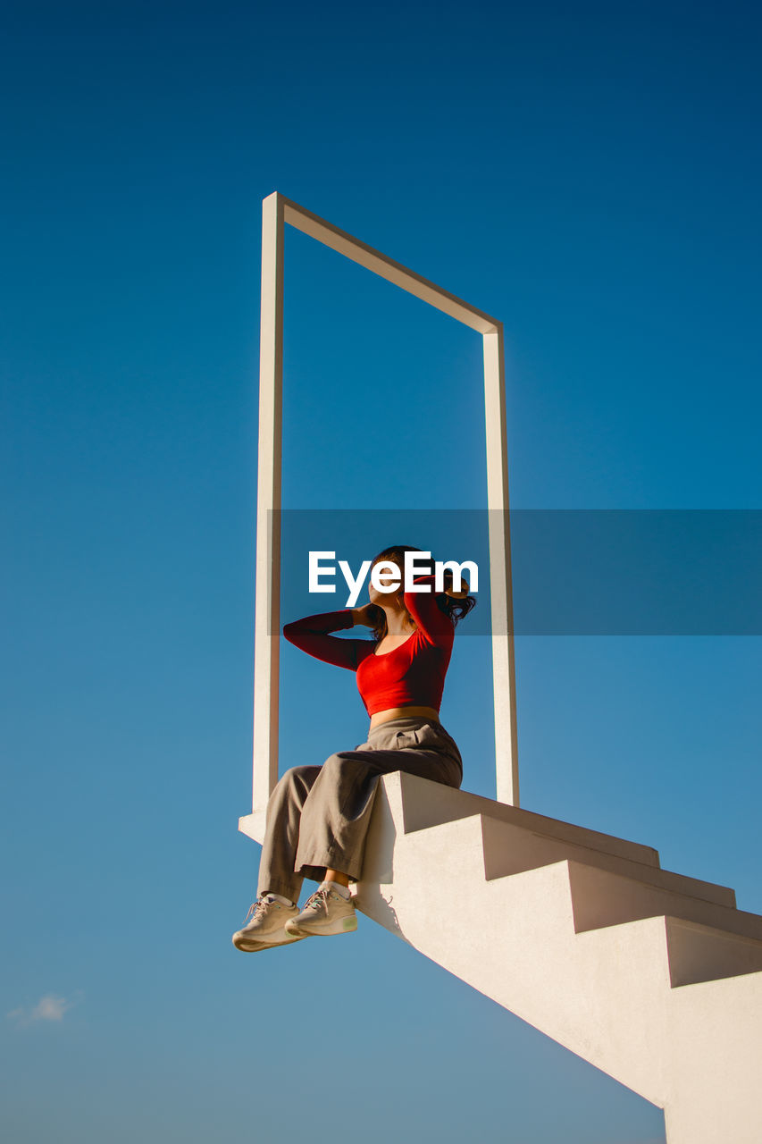 LOW ANGLE VIEW OF BOY AGAINST BLUE SKY