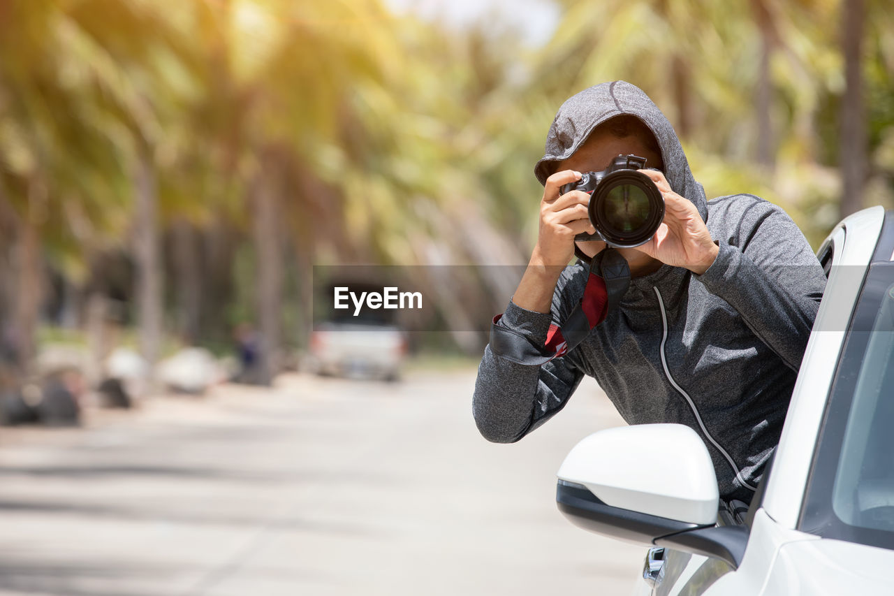 MAN PHOTOGRAPHING WITH UMBRELLA ON STREET IN CITY