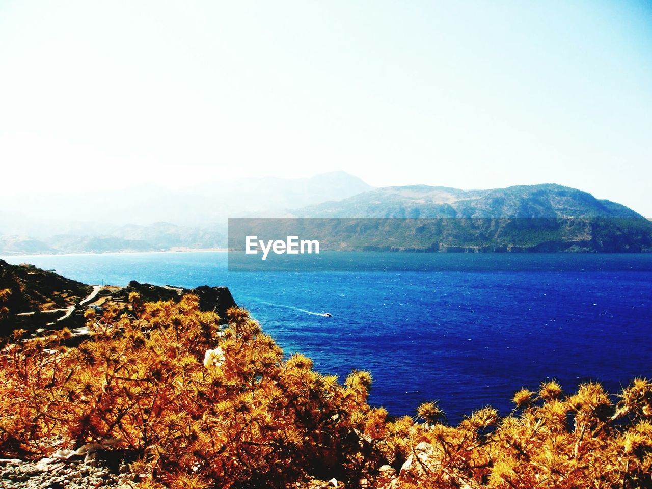 SCENIC VIEW OF SEA AND MOUNTAIN AGAINST CLEAR SKY