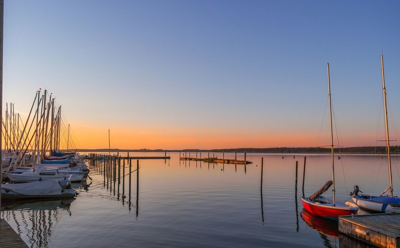 Boats moored in lake at sunrise