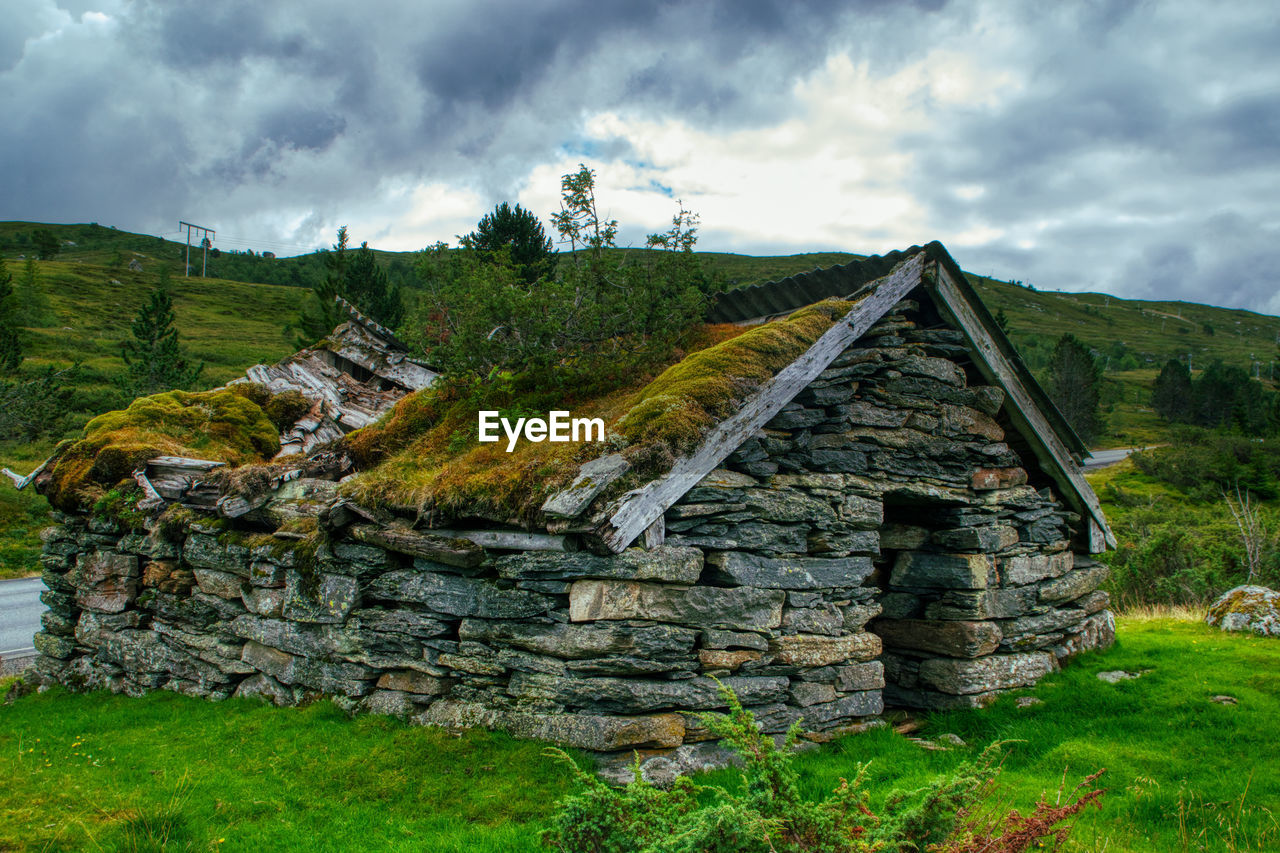 OLD RUIN ON FIELD BY BUILDING AGAINST SKY