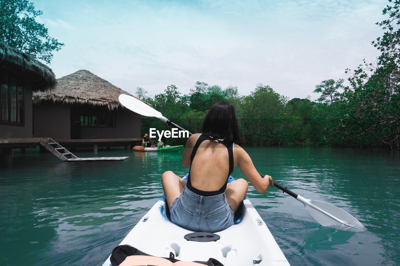 Rear view of woman sitting in rowboat against sky