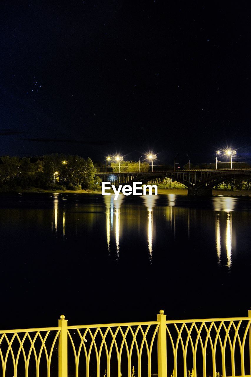 BRIDGE OVER RIVER AGAINST SKY AT NIGHT