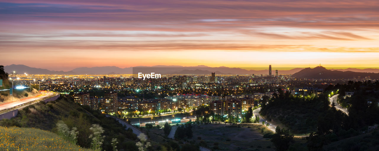 Illuminated buildings in city at sunset