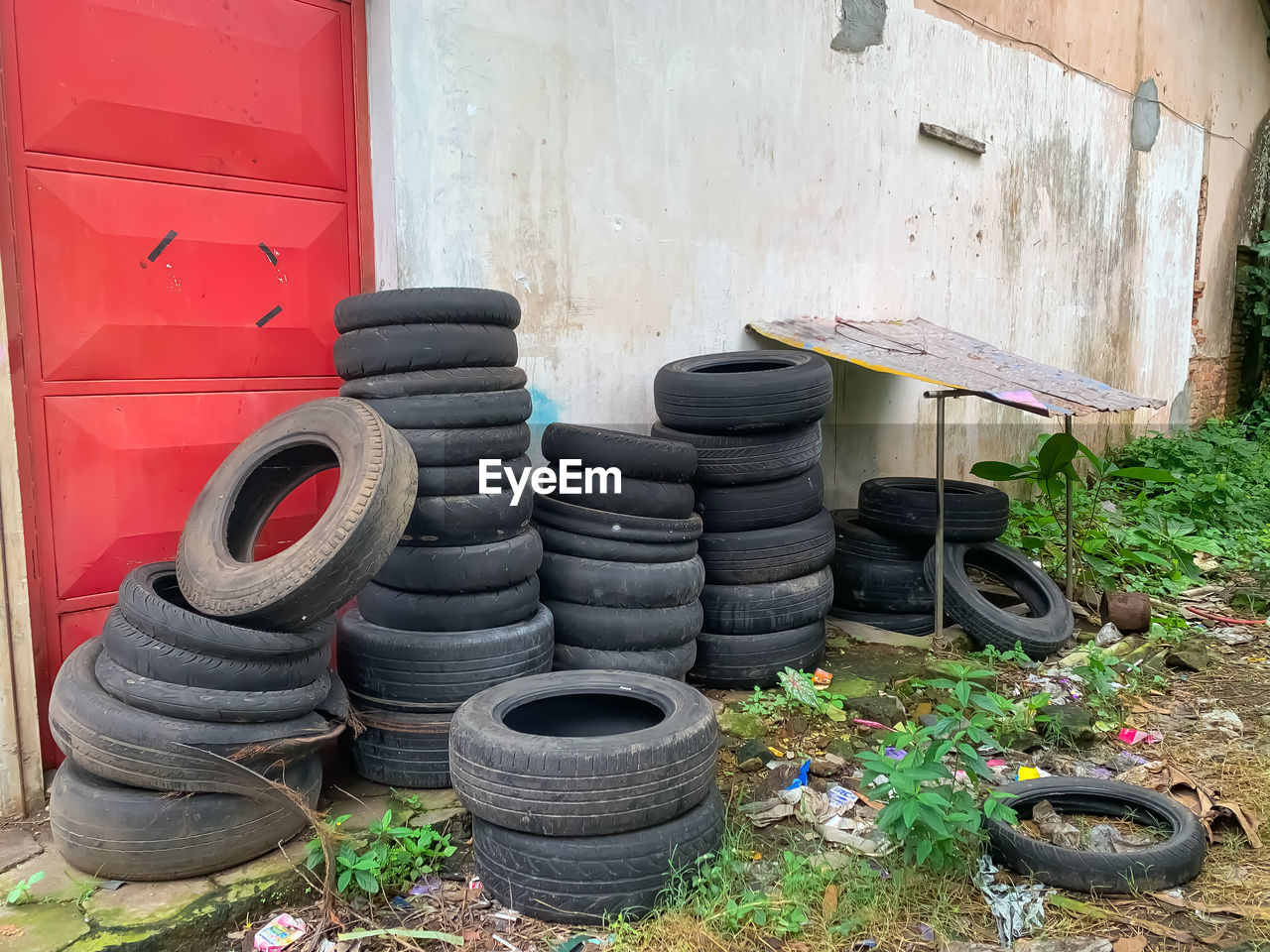 tire, natural rubber, wheel, synthetic rubber, no people, automotive tire, day, architecture, plant, nature, building, built structure, large group of objects, rubber, outdoors, building exterior, yard