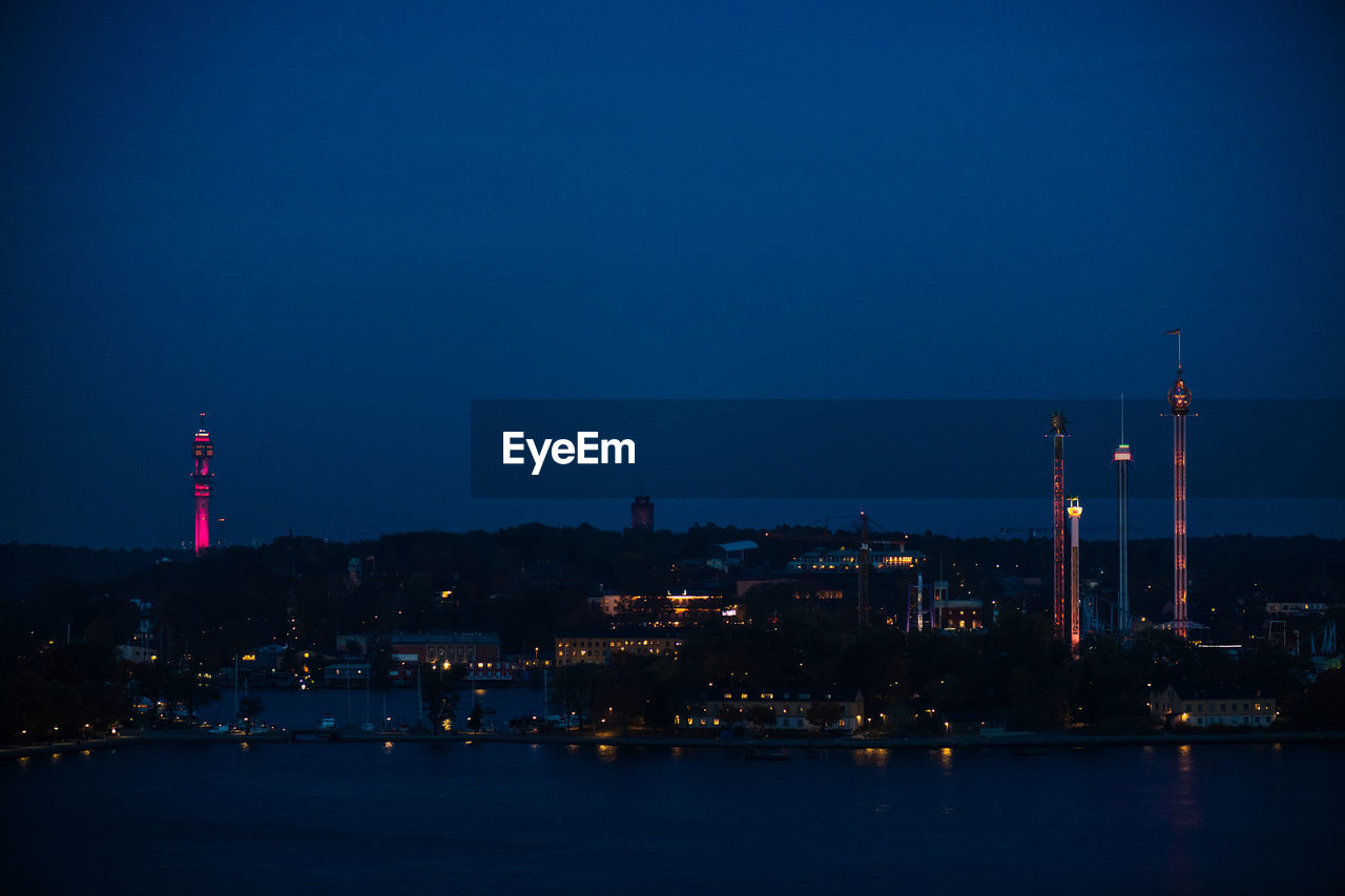 ILLUMINATED CITY AGAINST SKY AT DUSK