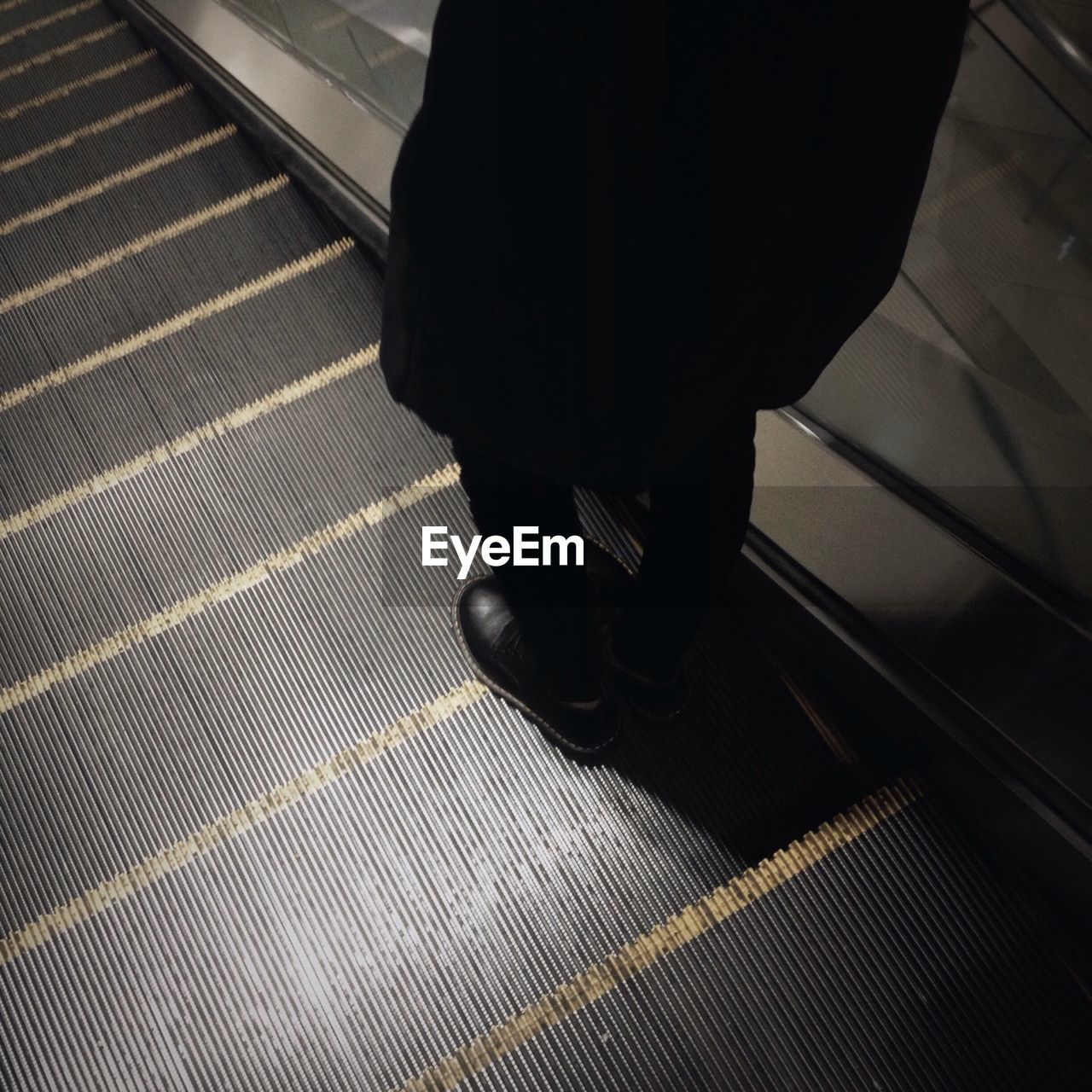 Low section of person standing on escalator