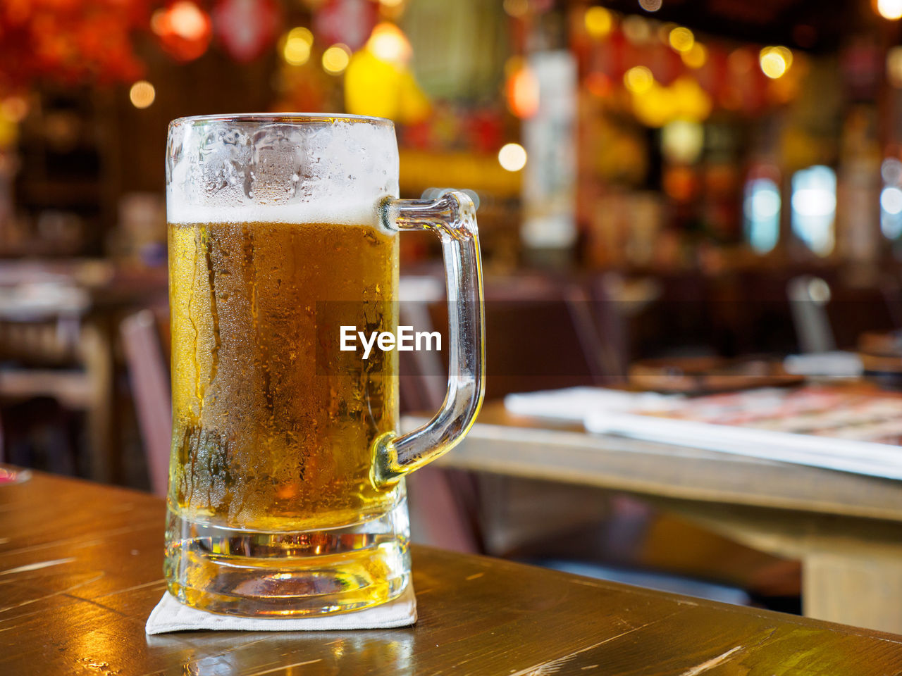 Closeup detail of a glass of beer on a tabletop at a japanese izakaya restaurant. bangkok, thailand. 