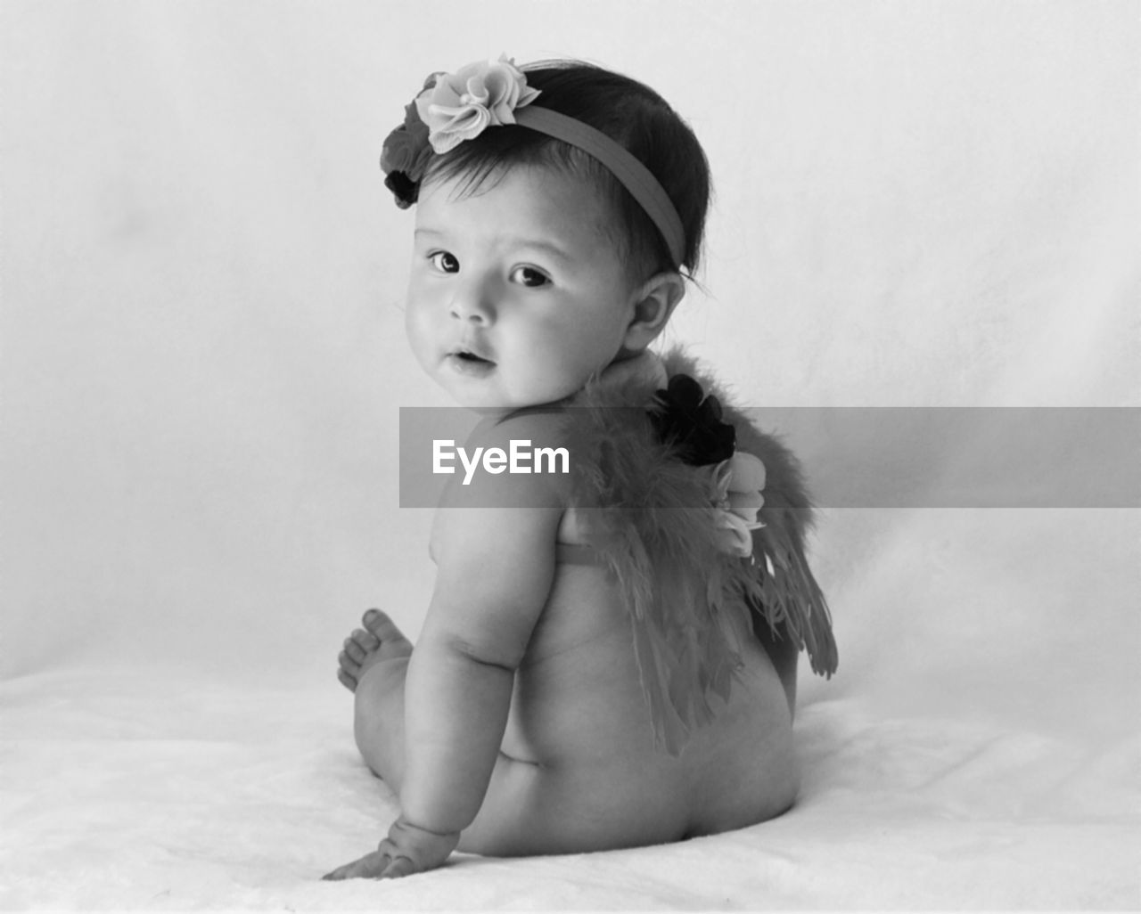 Portrait of cute toddler girl sitting on bed