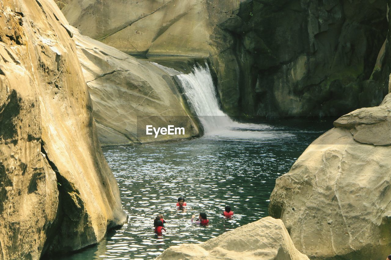 High angle view of friends swimming against waterfall