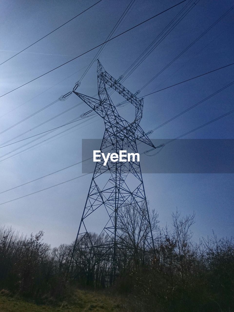 Low angle view of electricity pylon against clear blue sky