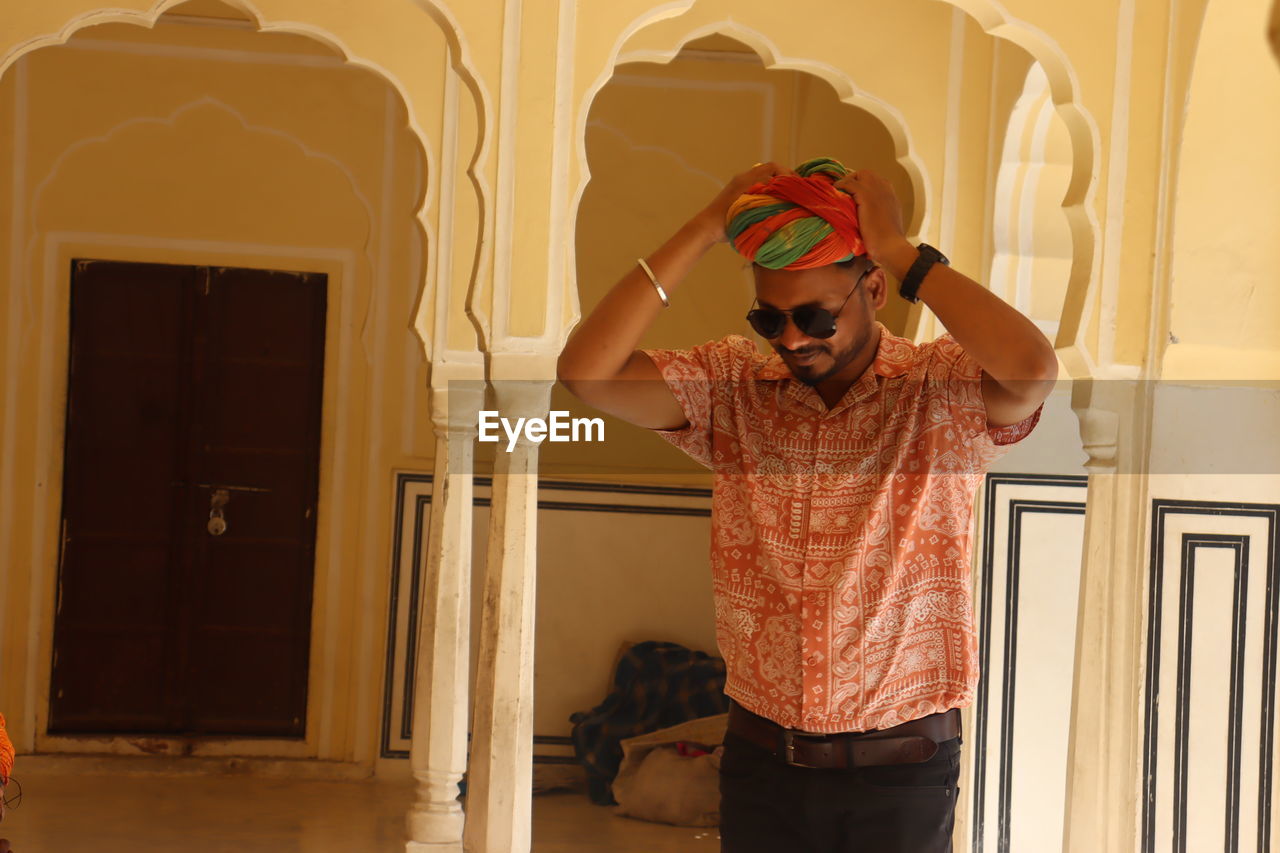 one person, standing, adult, indoors, front view, three quarter length, men, clothing, architecture, lifestyles, glasses, portrait, casual clothing, young adult, emotion, red, art, fashion, sunglasses