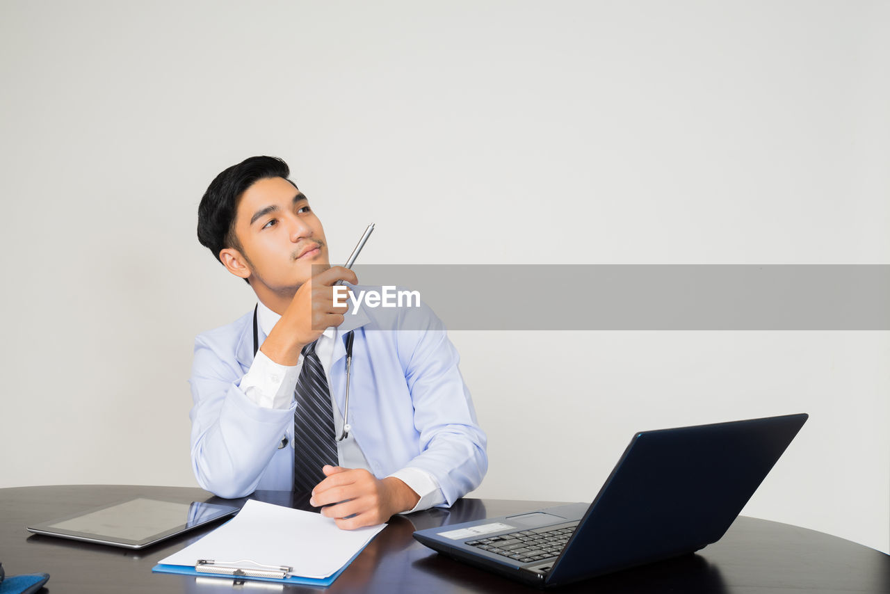 Doctor pointing up while sitting at desk in hospital