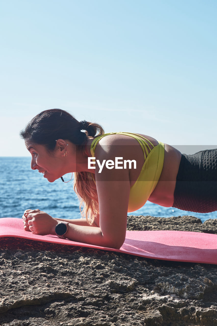 Latin woman, middle-aged, wearing sportswear, training, doing physical exercises, plank, sit-ups, 