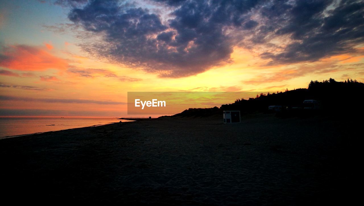 SCENIC VIEW OF BEACH AGAINST ORANGE SKY