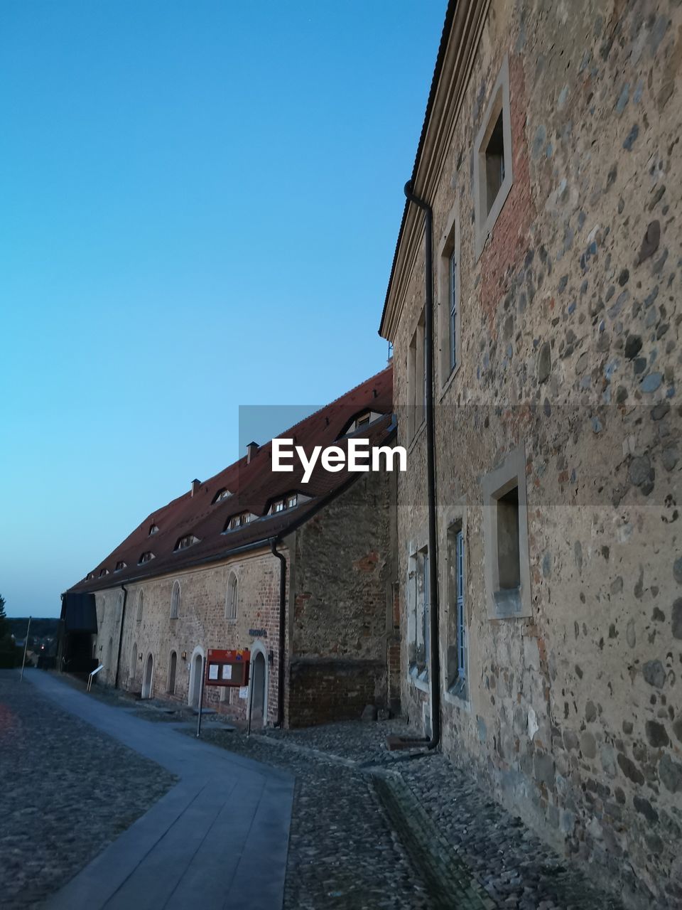 architecture, building exterior, built structure, sky, clear sky, building, town, street, wall, city, no people, blue, road, nature, house, day, residential district, the way forward, outdoors, history, old, wall - building feature, transportation, urban area, footpath, alley, the past, copy space, cobblestone