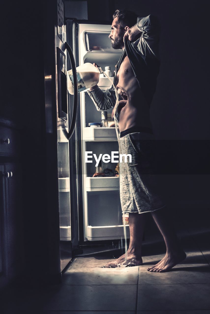 MAN STANDING IN KITCHEN AT HOME