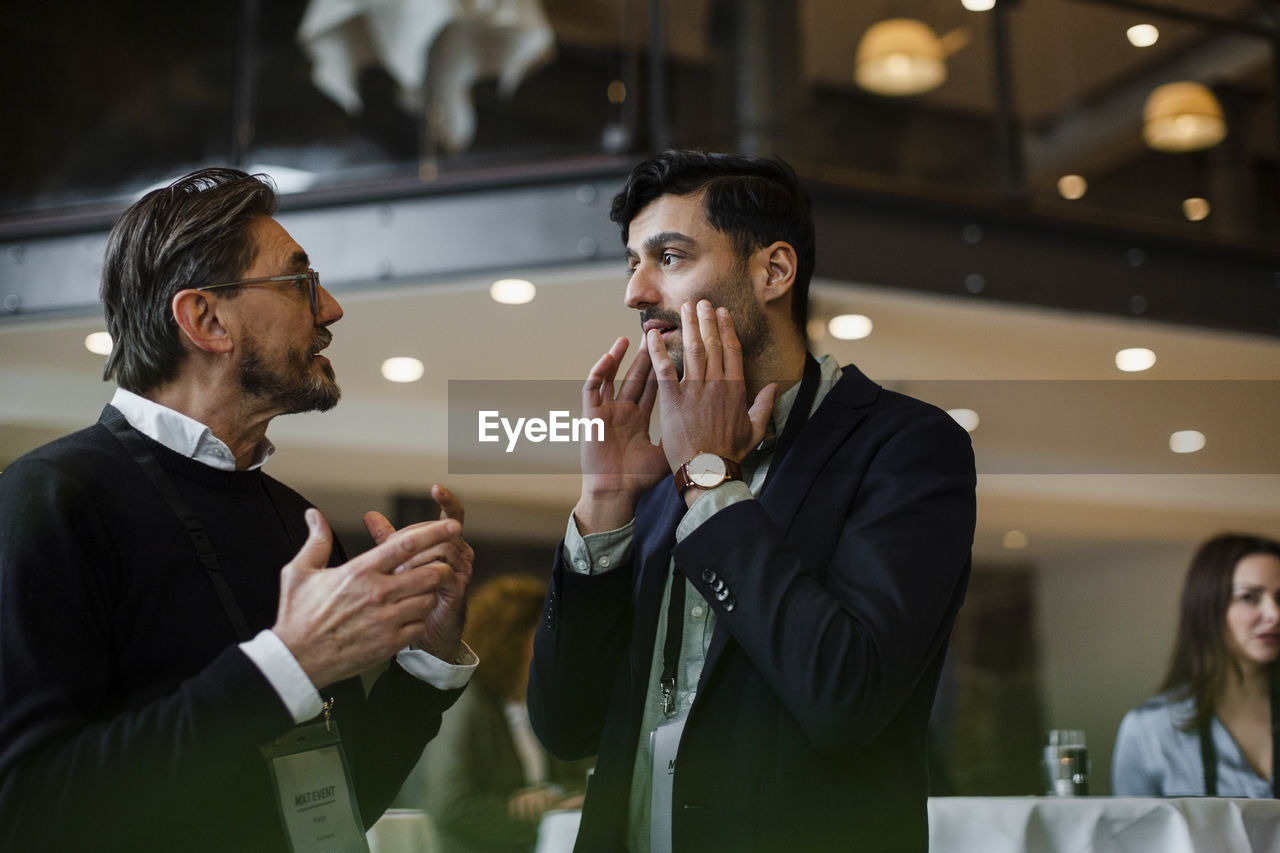 Businessmen gesturing while talking with each other during seminar