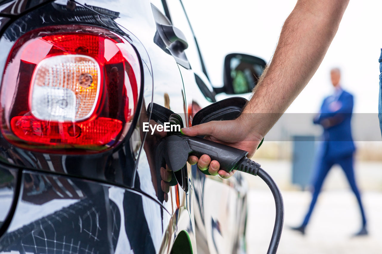 Electric car with plug-in socket at charge station charging battery