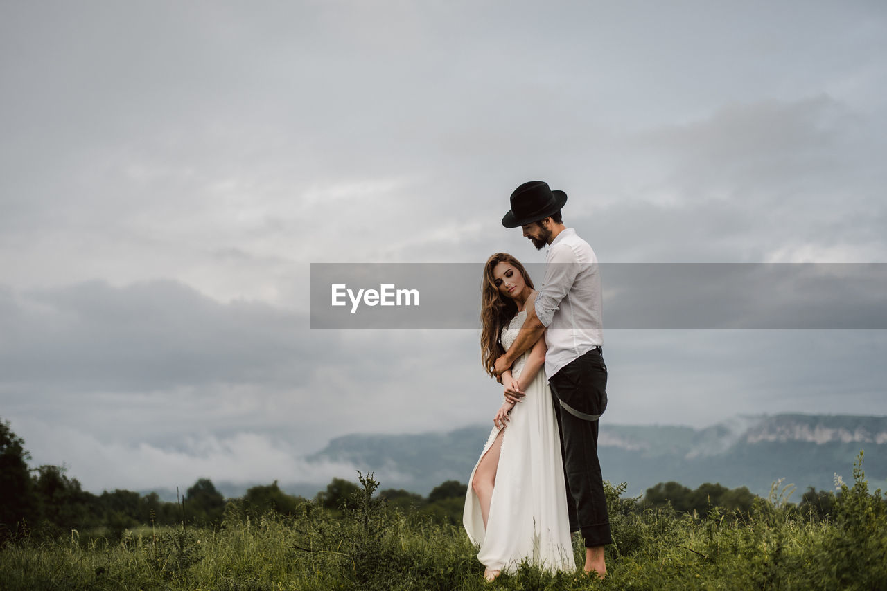 Full length of young couple standing on field