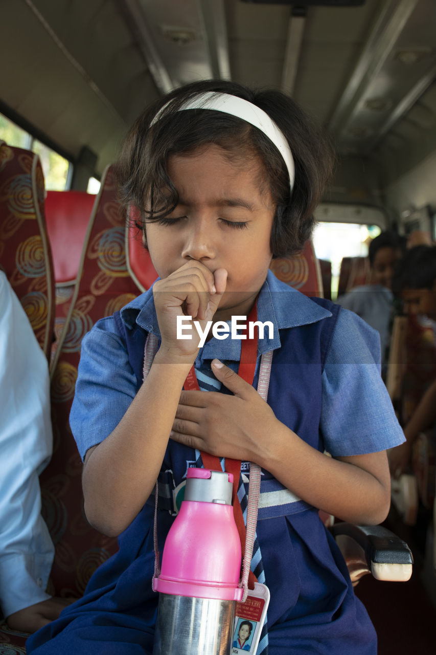 Girl coughing while sitting in bus