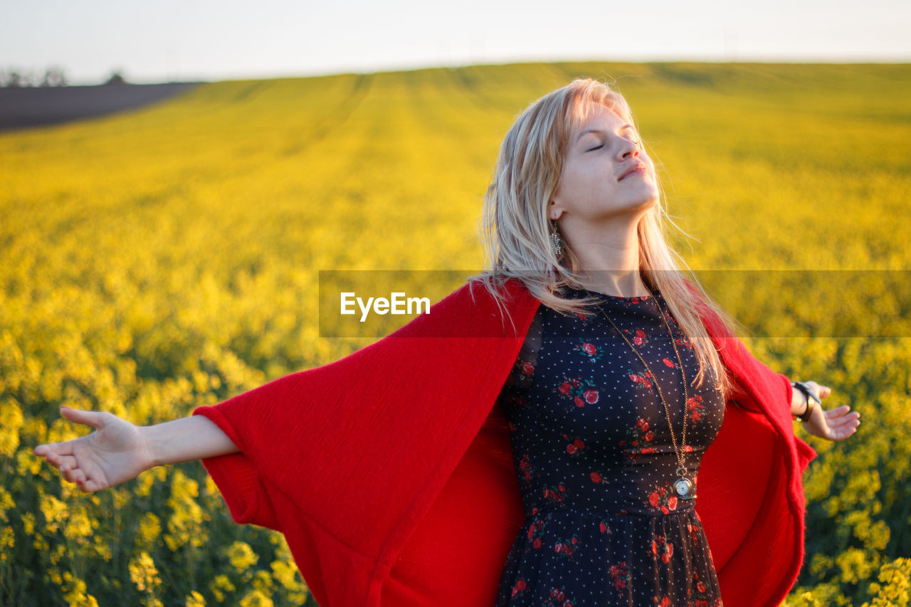 Woman with arms outstretched standing on field