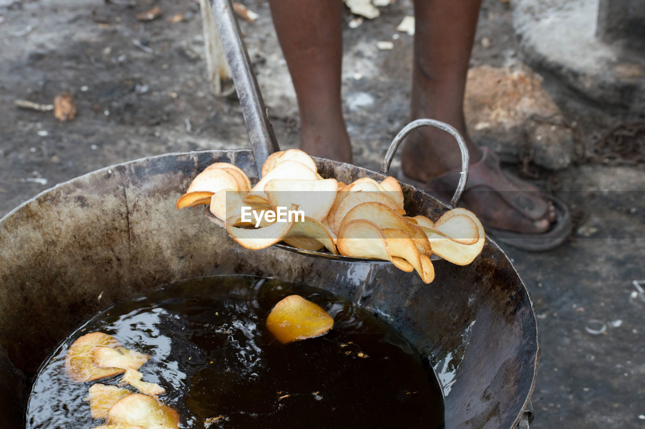 Low section of man frying potato chips outdoors