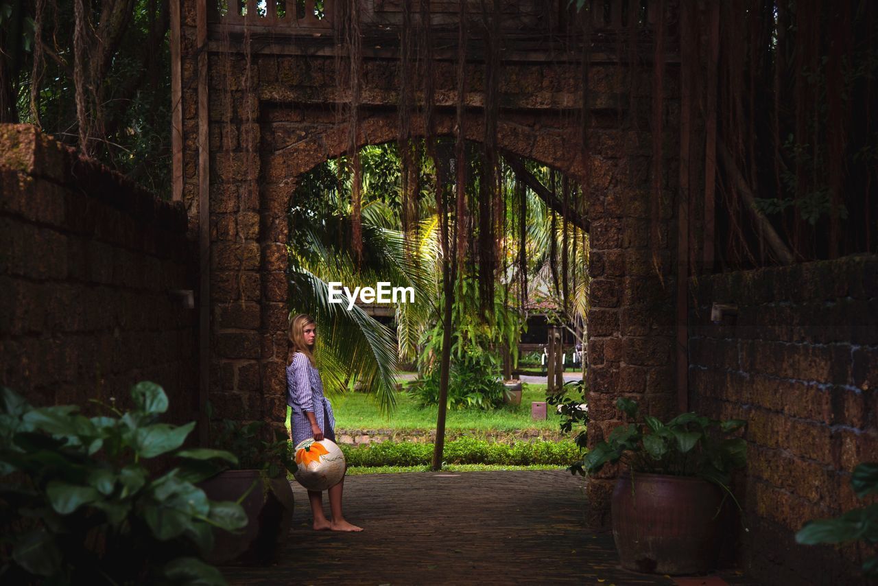 Portrait of teenage girl leaning against built structure 