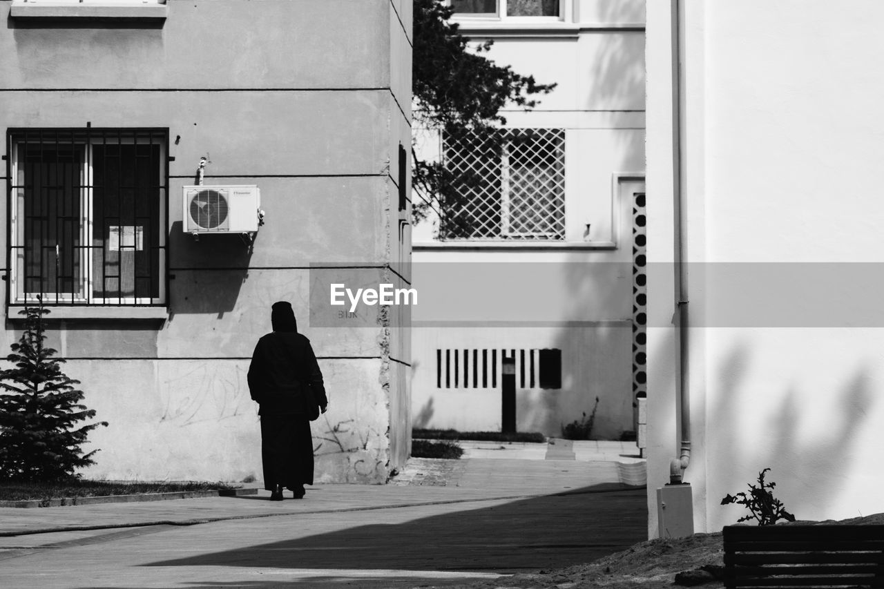 Rear view of woman wearing burka while walking against building
