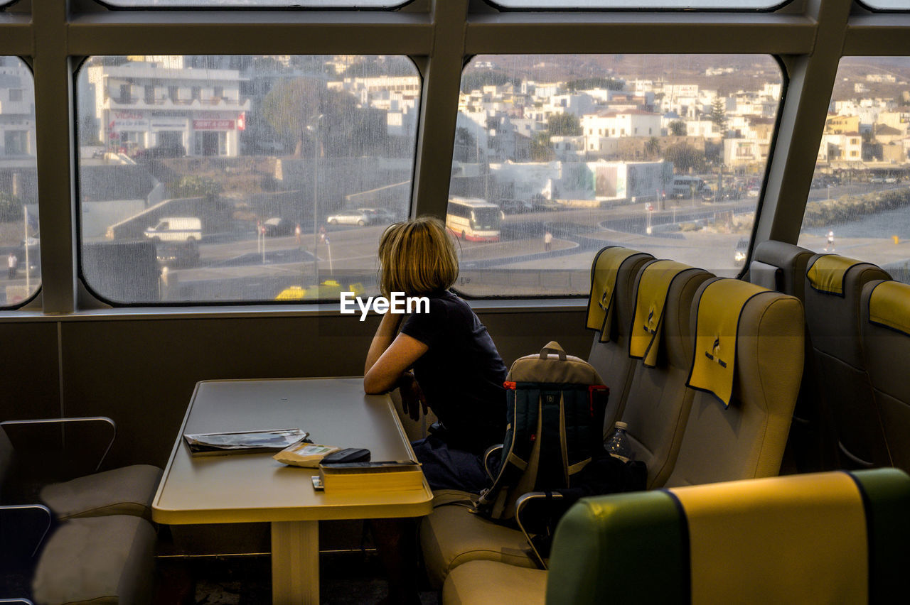 REAR VIEW OF MAN SITTING IN BUS