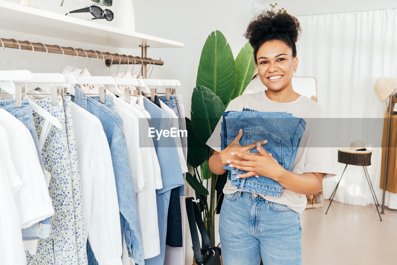 PORTRAIT OF HAPPY YOUNG WOMAN STANDING AGAINST WALL