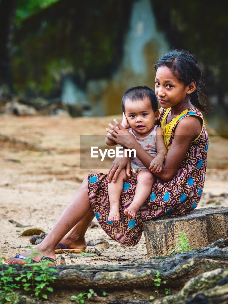 MOTHER AND GIRL SITTING ON STONE