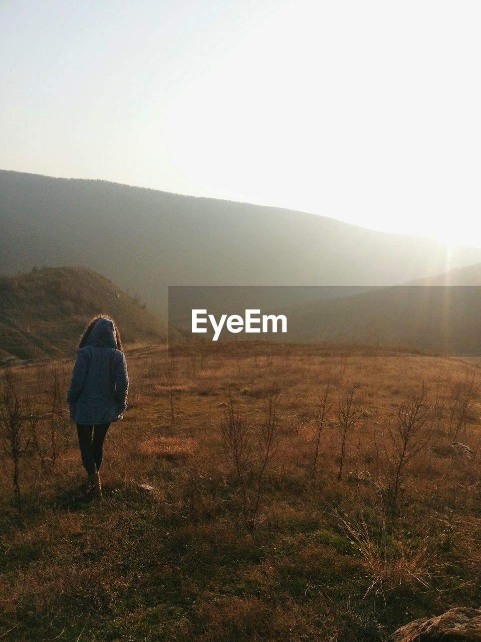 Rear view of woman walking on field against clear sky