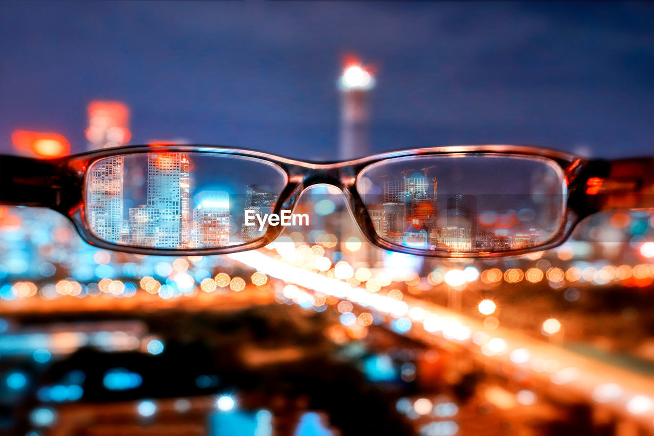 illuminated, glasses, close-up, focus on foreground, glass - material, nature, no people, fashion, transparent, sunglasses, eyeglasses, architecture, building exterior, selective focus, reflection, sky, outdoors, night, glowing, lighting equipment, personal accessory