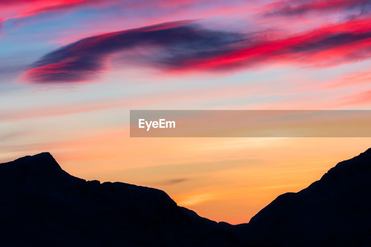 Scenic view of silhouette mountains against orange sky