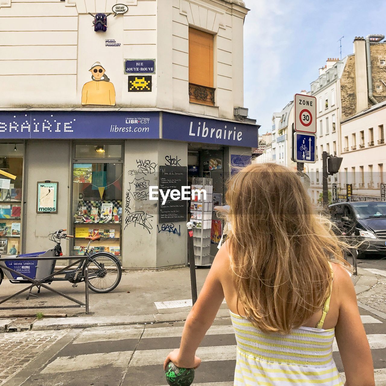 REAR VIEW OF WOMAN WITH BICYCLE ON CITY IN BACKGROUND