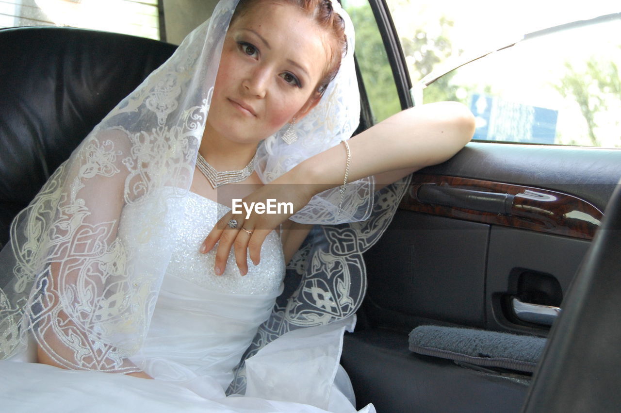 Portrait of beautiful bride traveling in car