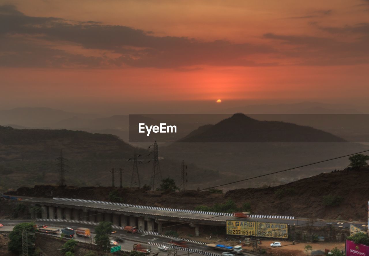 BRIDGE OVER MOUNTAINS AGAINST ORANGE SKY