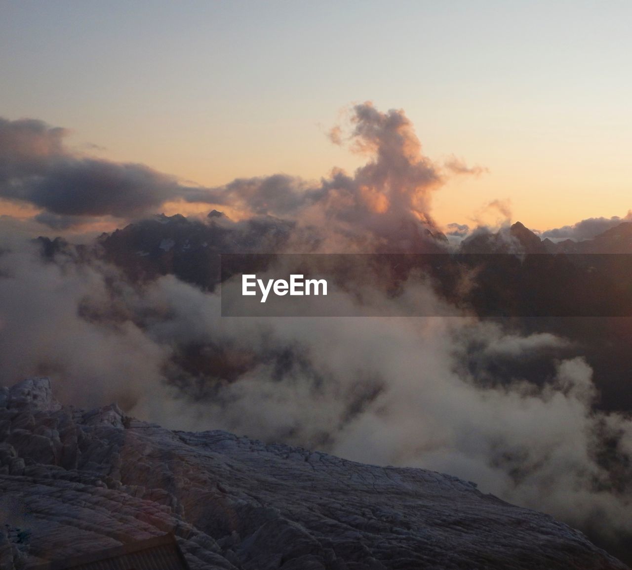 SMOKE EMITTING FROM VOLCANIC MOUNTAINS AGAINST SKY DURING SUNSET