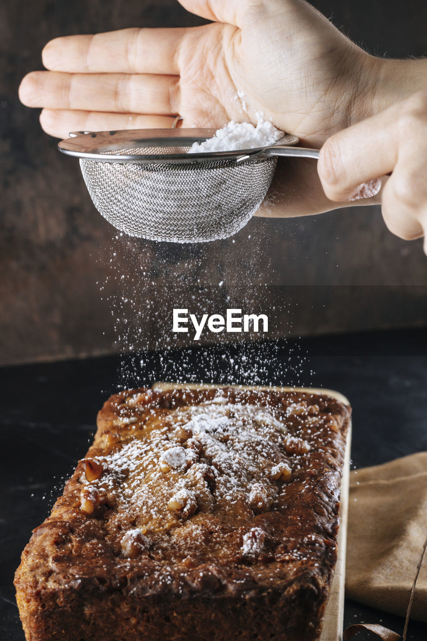 Woman pouring powdered sugar on pumpkin pie