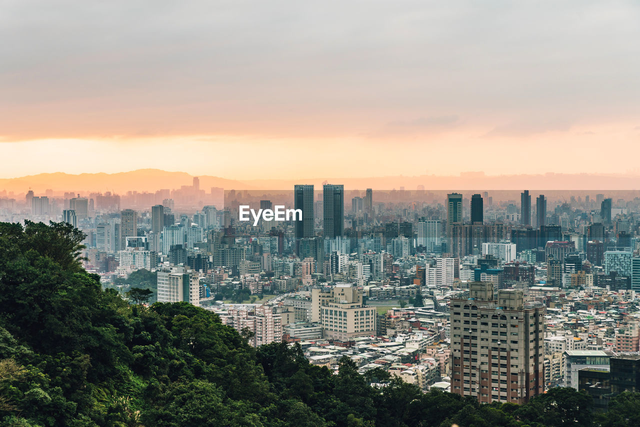 Aerial view of buildings in city against sky during sunset