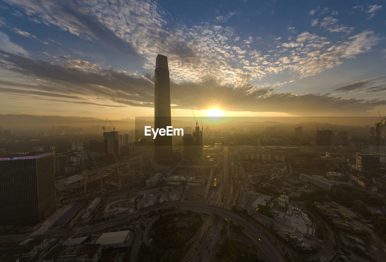 HIGH ANGLE VIEW OF MODERN BUILDINGS AGAINST SKY AT SUNSET