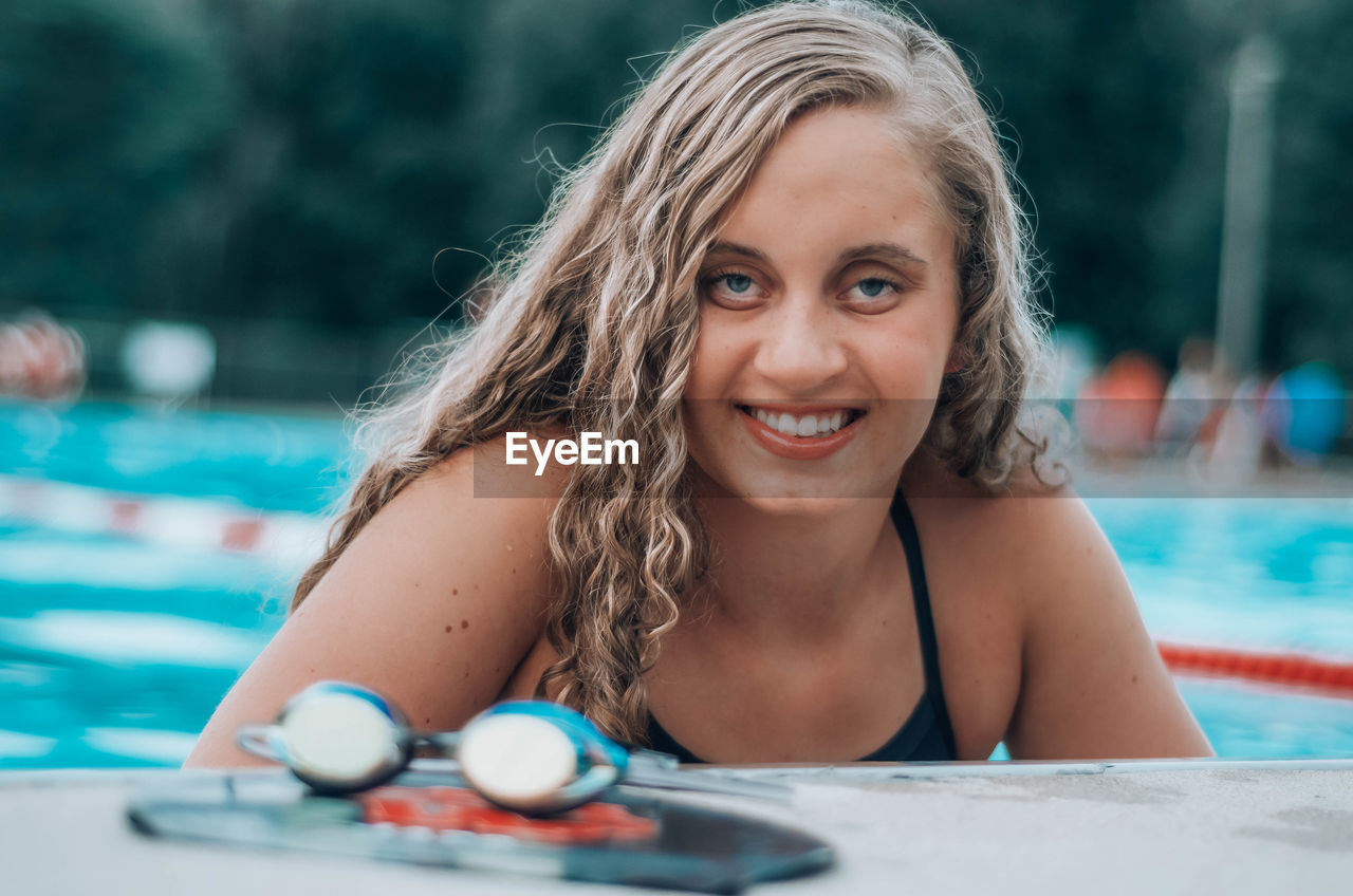 PORTRAIT OF A SMILING YOUNG WOMAN SWIMMING POOL