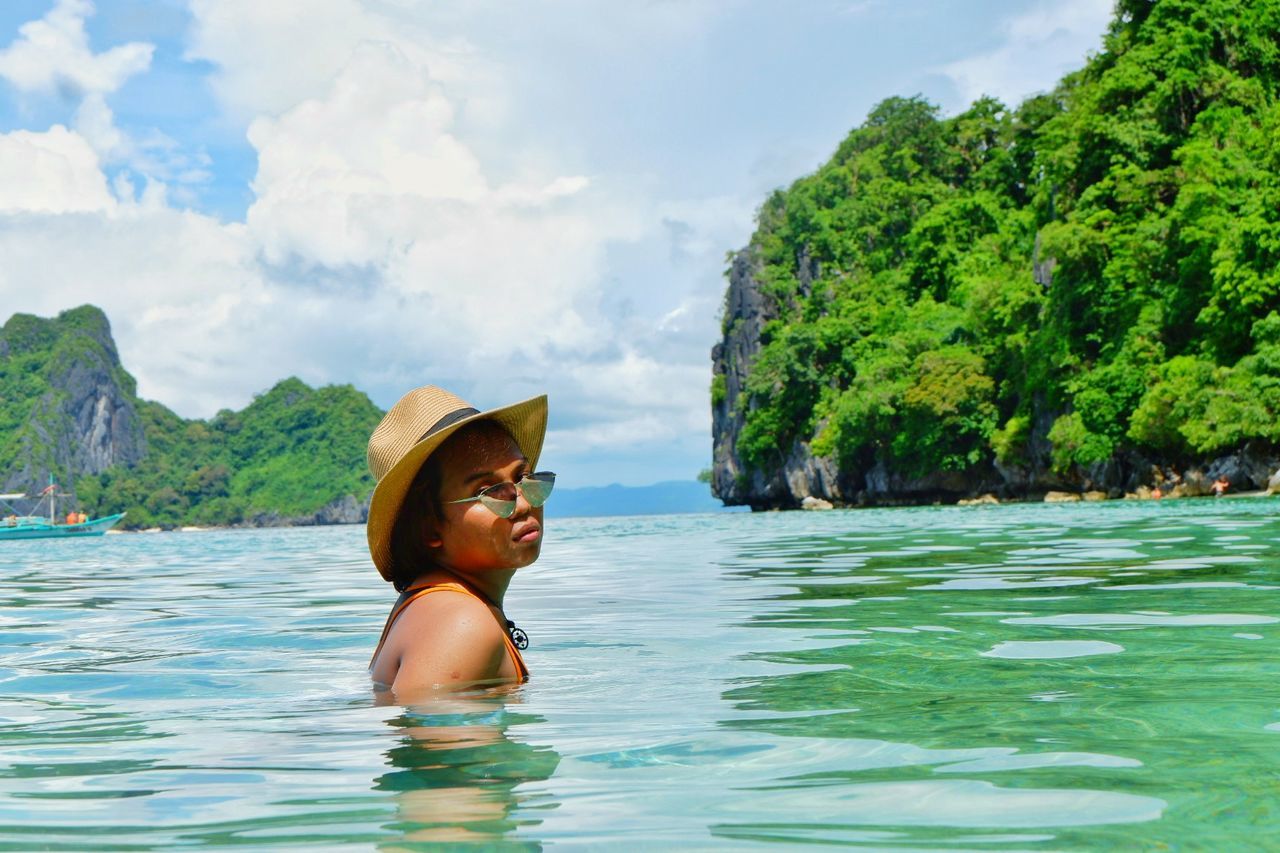 Side view of woman in sea against sky