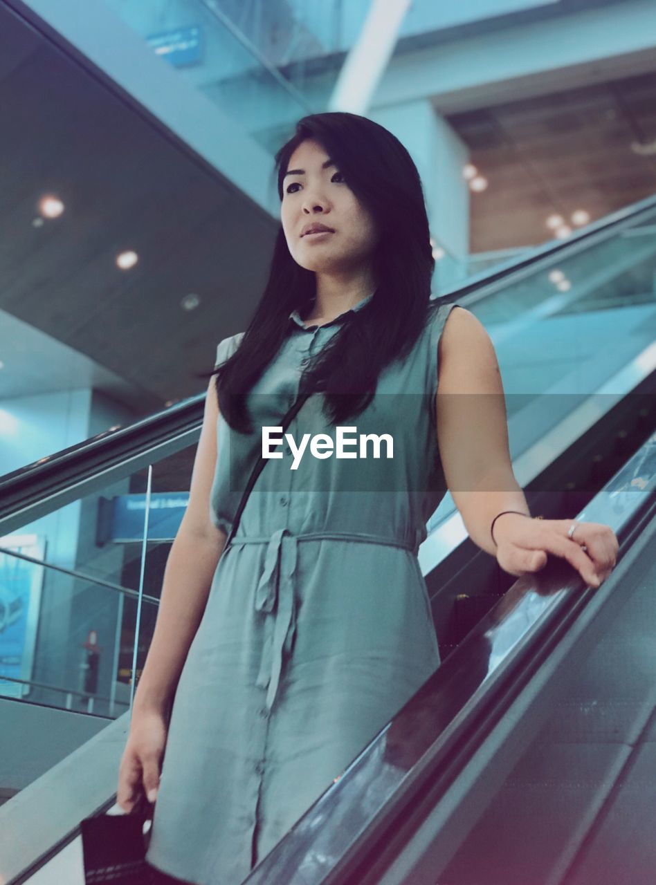 Young woman standing on escalator