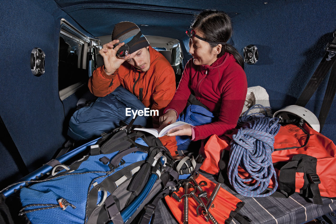 Couple looking at guide book in the back of their camper van