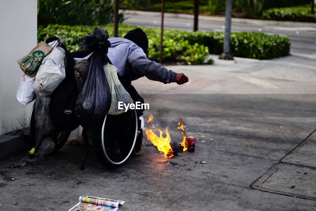 Homelessness person on wheelchair extinguishing fire